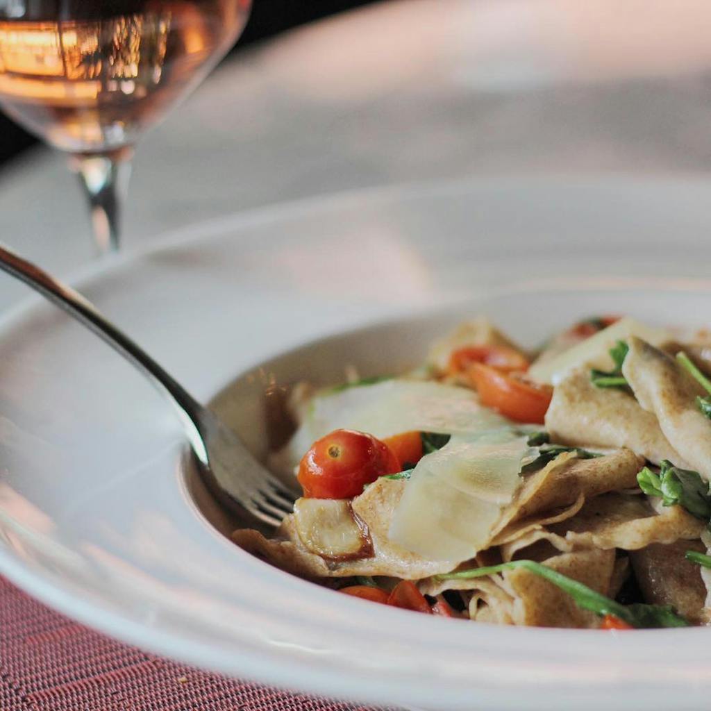 Delicious pasta with cherry tomatoes paired with wine, highlighting Italian cuisine and culinary art.